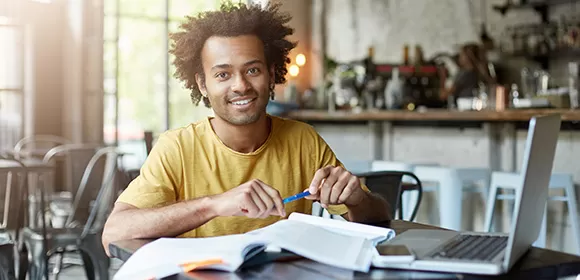 Estudante animado aplicando dicas de motivação para estudar inglês diante do computador.